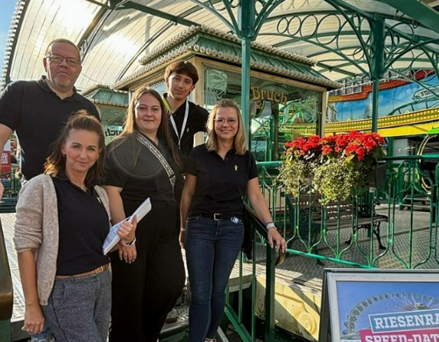 drei Frauen und zwei Männer stehen auf einer Stahltreppe im freien