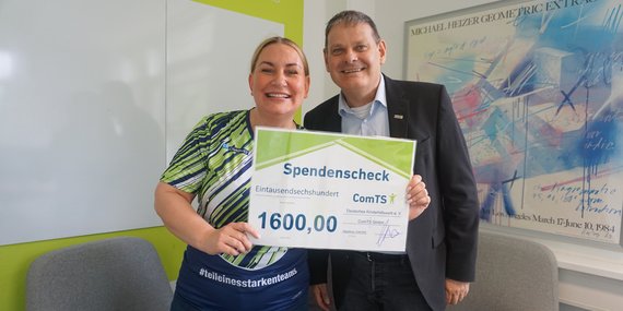Frau und Mann halten zusammen den Spendencheck hoch